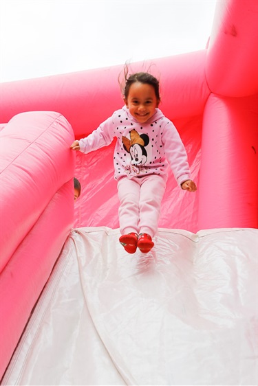 Young girl smiling and sliding down jumping castle slide