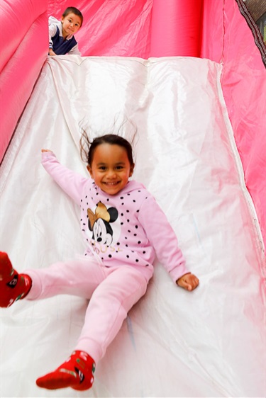 Young girl smiling while sliding down jumping castle slide