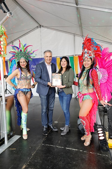 Mayor Frank Carbone and young woman holding certificate while posing with two female Brazilian dancers