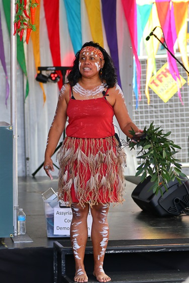 Aboriginal woman standing on stage while holding sage