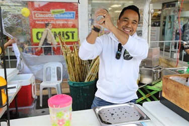 Man smiling and posing while preparing sugar cane juice drink