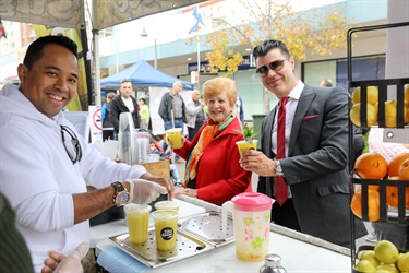Man smiling and posing with guests holding sugar cane juice drinks