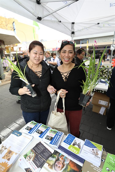 Two women smiling and posing while holding small potted plants