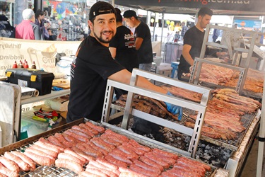 Young man smiling while cooking assorted meats on barbecue