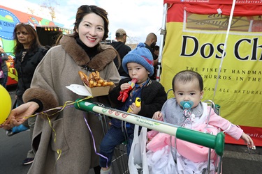 Mother smiling and posing with her two young children while holding a box of churros