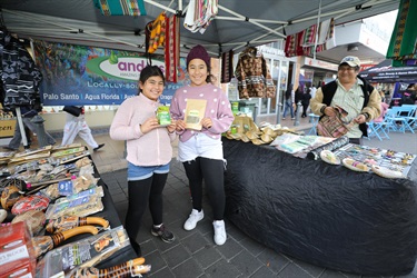 Two young girls smiling and posing while holding stall merchandise