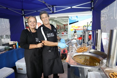 A man and woman smiling and posing while cooking churros