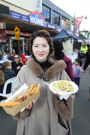Woman smiling and posing while holding a box of churros and a plate of pasta