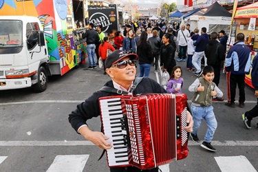Man smiling and posing while playing a red accordion