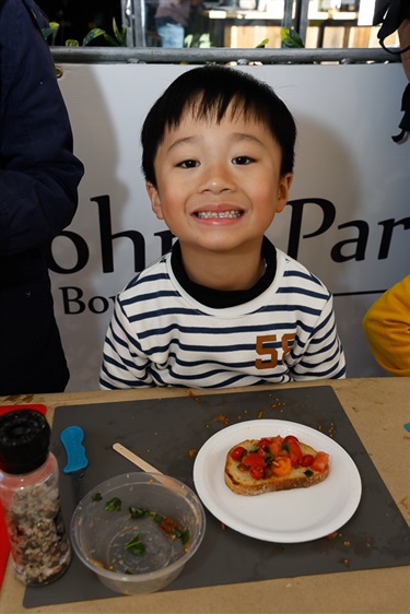 Young boy smiling with his plate of bread and cherry tomatoes