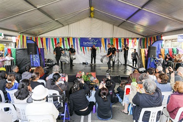 Crowd of seated guests watching group of young men playing the drums on the stage