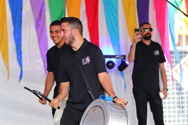Young men on stage smiling while playing the drums