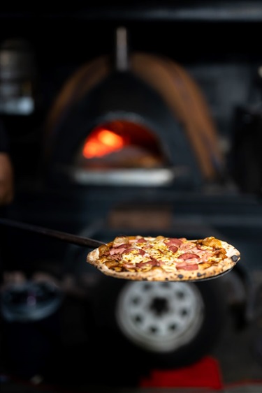 Pizza in front of woodfired oven