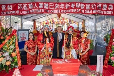 Mayor Frank Carbone smiling and posing with Chinese Associations of the Great Western Sydney representatives dressed in traditional red Chinese clothing