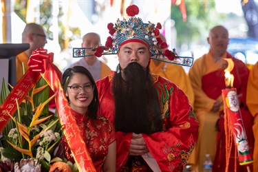 Man and woman wearing traditional red Chinese clothing smiling and posing