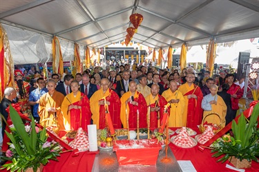 Crowd of monks, Councillors and guests holding incense sticks while praying