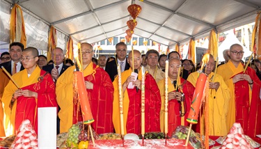 Group of monks and councillors holding incense sticks while praying