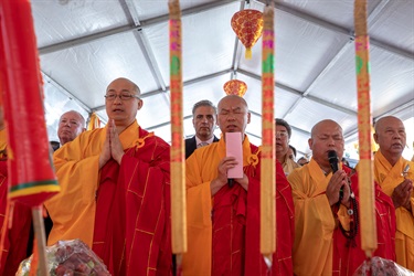 Group of monks joining their hands together to pray in front of burning incense sticks