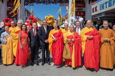 Mayor Frank Carbone smiling and posing with Councillors, monks and colourful lion dancers