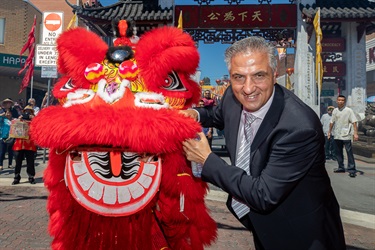 Mayor Frank Carbone smiling and posing with red lion dance puppet head
