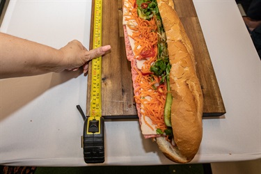Close up of Vietnamese bread roll next to measuring tape reading 153 centimetres