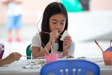 Young girl painting small ceramic object