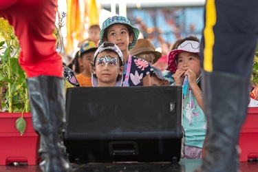 Young children watching the performers on the stage