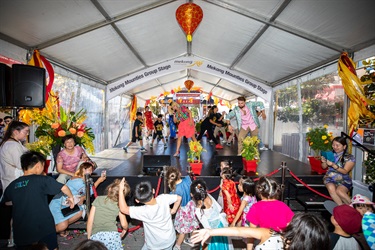Two performers on the stage instructing dance moves to crowd of young children