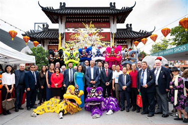 Mayor, Councillors and sponsors smiling and posing with lion dancers in front of Pai Lau gate