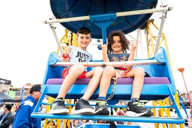 Two young boys on the Ferris wheel smiling and posing for a photo