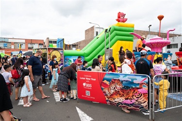 People lining up for the jumping castle and spinning tea cup rides at Arthur street car park