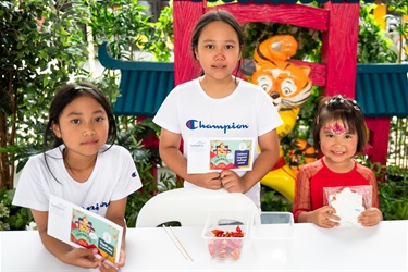Three young girls holding their prizes after competing in the chopstick challenge