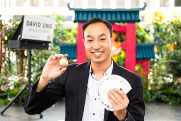 David Ung smiling and posing while holding an egg and a fanned out deck of cards