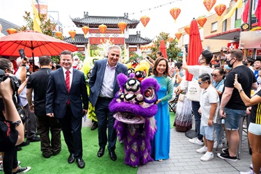 Mark Coure, Frank Carbone and Dai Le smiling and posing with a child lion dance performer in a purple lion costume at Freedom Plaza amongst the festivities.