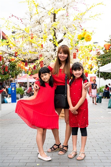 Mother and two daughters all wearing red and posing in front of tree decoration at Freedom Plaza