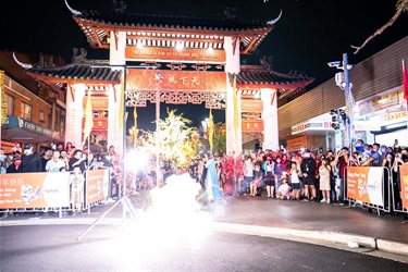 Fire crackers exploding with a large crowd watching in front of the Pai Lau gate