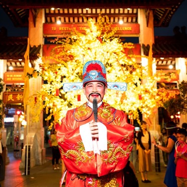 God of Fortune in front of a yellow lit tree and Pai Lau Gate