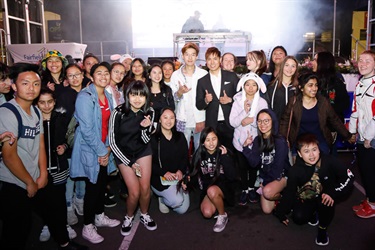 SBS Pop Asia Host Andy Trieu and Korean idol Kevin Kim smiling and posing with group of fans