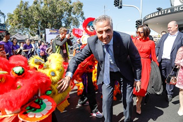 Mayor Frank Carbone smiling and posing while petting a yellow lion dancing puppet