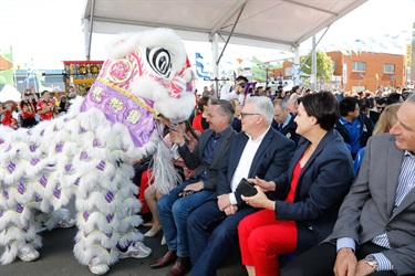 Crowd of guests watching lion dancing performers in white and purple costume performing on stilts