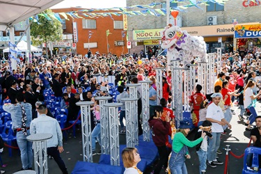 Crowd of guests watching lion dancing performers in white and purple costume performing on stilts