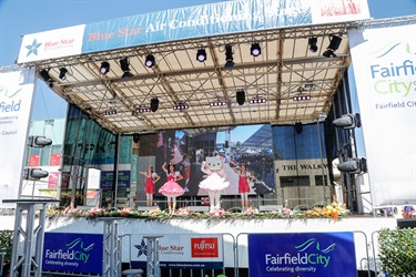 Hello Kitty costumed character and three young women wearing red overalls performing on the stage