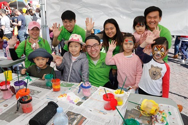 Stall holders smiling and posing with young children with colourful face paint