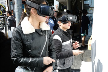Two young children wearing virtual reality head sets and holding hand controllers