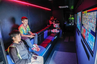 Two young boys sitting down and holding hand controllers while playing video game