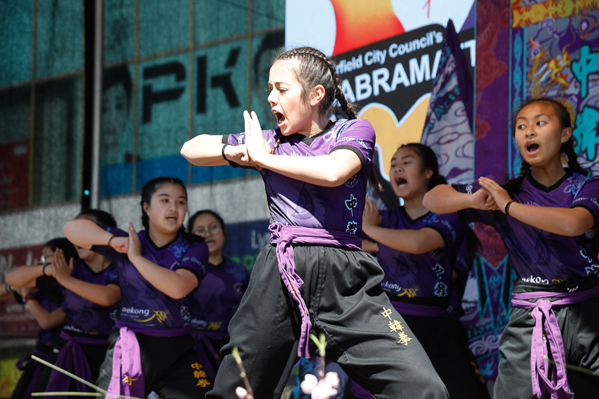 Young girls wearing purple uniform performing martial arts routine on stage