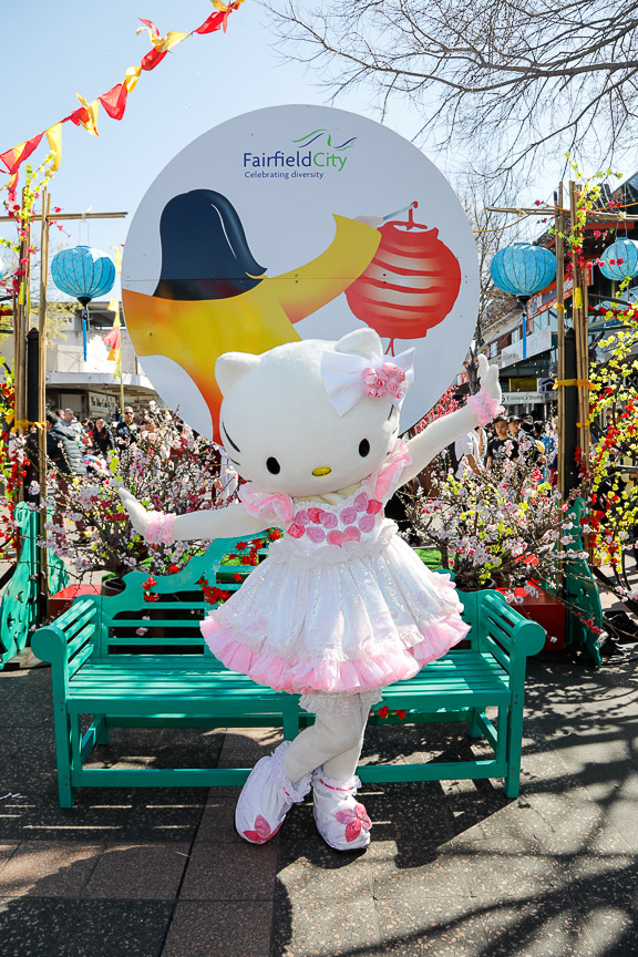 Hello Kitty costumed character posing in front of Cabramatta Moon Festival banner