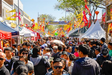 Crowd of guests travelling through John Street and walking under the red and yellow flags