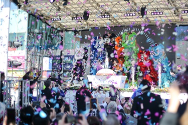 Premier Gladys Berejiklian cuts moon themed cake surrounded by colourful lion dancing puppets while blue and purple confetti falls