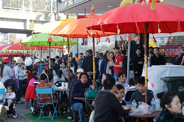 Families sitting around tables shaded by colourful umbrellas